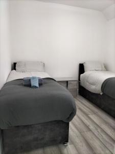 1 Schlafzimmer mit 2 Einzelbetten und Holzboden in der Unterkunft Remaj Service Accommodation, Sleep 7 in Dagenham