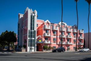 un grand bâtiment rouge avec des voitures garées devant lui dans l'établissement Days Inn by Wyndham Santa Monica, à Los Angeles