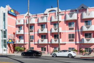 two cars parked in front of a pink building at Days Inn by Wyndham Santa Monica/Los Angeles in Los Angeles