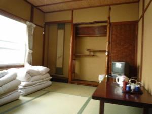 a room with a bunk bed and a table with a television at Daiya Ryokan in Kyoto