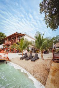 a group of chairs sitting on a beach next to a building at El Búho Lagoon Bacalar in Bacalar