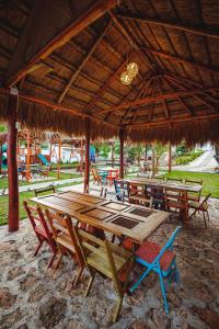 un gruppo di tavoli e sedie in legno sotto un ombrellone di paglia di El Búho Lagoon Bacalar a Bacalar Altre 87 foto