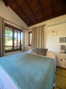 a bedroom with a large blue bed with a window at Maui Suítes e Chalés in Arraial d'Ajuda