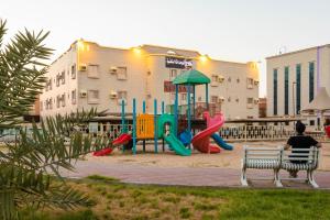 a man sitting on a bench in a playground at سوار للوحدات السكنية in Taif