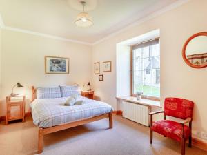 a bedroom with a bed and a chair and a window at The Old Laundry in Grantown on Spey