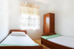 two beds in a room with a window at Apartments by the sea Mimice, Omis - 656 in Mimice