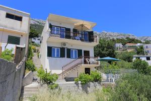 a white house with a balcony and an umbrella at Apartments with parking space Marusici, Omis - 657 in Mimice