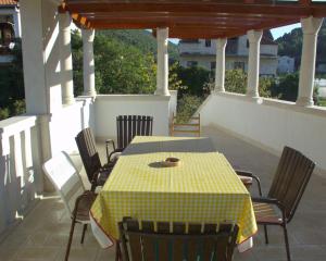 a table and chairs on a porch with a yellow and white checkered table at Holiday house with WiFi Postira, Brac - 701 in Postira