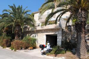 a motorcycle parked in front of a building with palm trees at Apartments by the sea Milna, Brac - 733 in Milna