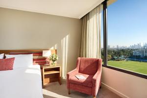 a bedroom with a bed and a chair and a window at View Melbourne in Melbourne