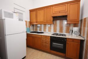 a kitchen with a white refrigerator and wooden cabinets at Apartments by the sea Stomorska, Solta - 778 in Stomorska