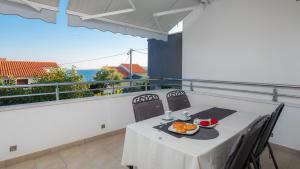 a table with a plate of food on a balcony at Apartments by the sea Seget Vranjica, Trogir - 978 in Seget Vranjica