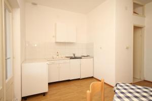 uma cozinha branca com armários brancos e uma mesa em Apartments and rooms by the sea Lucica, Lastovo - 990 em Lastovo