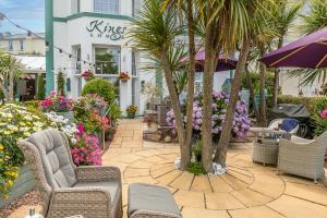 a patio with chairs and palm trees in front of a building at Kings Lodge in Torquay