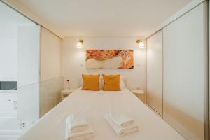 1 dormitorio con 1 cama blanca grande con almohadas de color naranja en Historic & Sunny Mezzanine Bolhão by Vacationy, en Oporto