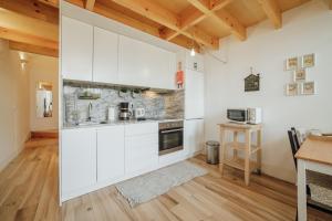 cocina con armarios blancos y suelo de madera en Historic & Sunny Mezzanine Bolhão by Vacationy, en Oporto