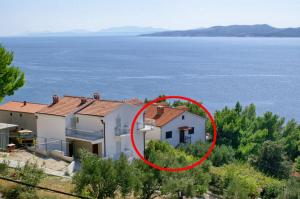 a house with a red circle in front of the water at Apartments with a parking space Marusici, Omis - 1041 in Mimice