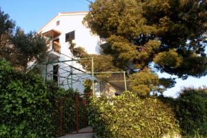 a white house with a gate and some bushes at Apartments with a parking space Marusici, Omis - 1041 in Mimice