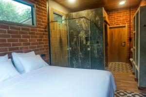 um quarto com uma cama e uma cabina de duche em vidro em Pacha Eco Lodge Glamping & Hotel em Archidona