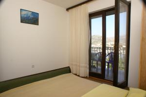 a bedroom with a bed and a window with a balcony at Apartment Seget Vranjica 1050b in Seget Vranjica