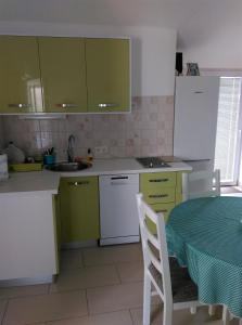 una cucina con armadi verdi e bianchi e un tavolo di Apartments by the sea Zdrelac, Pasman - 689 a Ždrelac