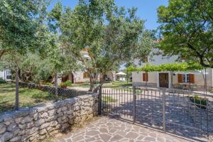a stone fence in front of a house with trees at Apartments with a parking space Punta kriza, Cres - 867 in Punta Križa