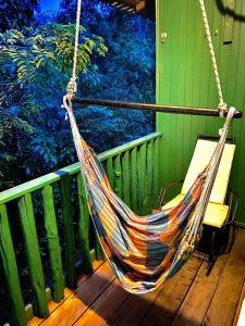 a hammock hanging from a porch with a green fence at Amazonia Jungle Hotel in Iranduba