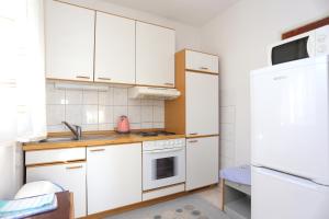a kitchen with white cabinets and a white refrigerator at Apartments with parking space Marusici, Omis - 954 in Mimice