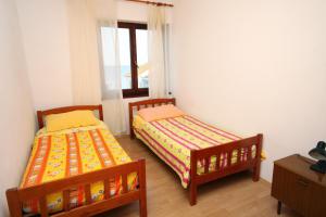 2 Betten in einem kleinen Zimmer mit Fenster in der Unterkunft Apartments by the sea Ugljan - 846 in Ugljan