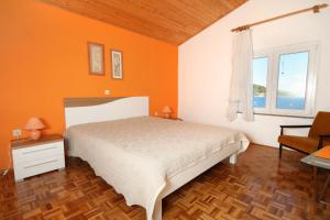 a bedroom with orange walls and a bed and a window at Apartments by the sea Kali, Ugljan - 837 in Kali