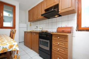 a kitchen with wooden cabinets and a black stove top oven at Apartment Zman 887a in Žman