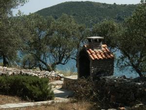 a brick chimney sitting next to a stone wall at Secluded fisherman's cottage Krknata, Dugi otok - 888 in Žman +13 photos