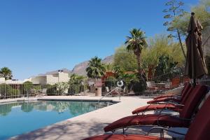een groep stoelen en een zwembad met een parasol bij Tucson Townhome 11 Mi to Dtwn - Long-Term Stays! in Tucson