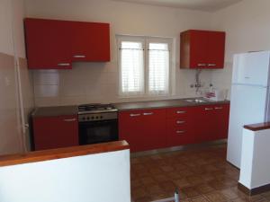 a kitchen with red cabinets and a white refrigerator at Seaside holiday house Veli Rat, Dugi otok - 875 in Veli Rat +15 photos
