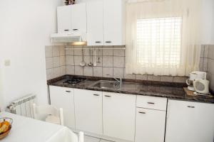 een keuken met witte kasten en een wastafel bij Family friendly seaside apartments Vodice - 928 in Vodice
