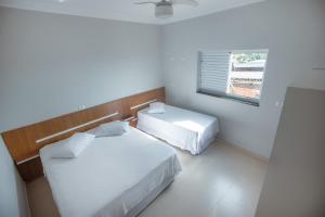2 camas en una habitación blanca con ventana en Souza Reis Apart - Unidade 1, en São Thomé das Letras