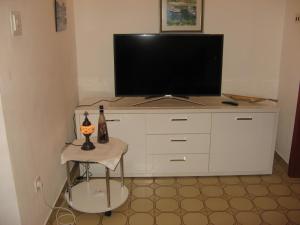 uma televisão numa cómoda branca com um banco em Apartment Pisak 967b em Mimice