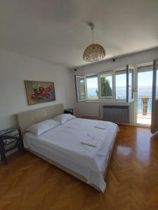 a bedroom with a large white bed in a room with windows at Apartments by the sea Stanici, Omis - 1031 in Tice
