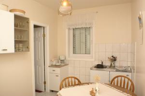 a white kitchen with a table and a sink at Apartments and rooms with parking space Sumartin, Brac - 757 in Sumartin +37 photos