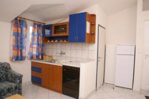 eine Küche mit blauen Schränken und einem weißen Kühlschrank in der Unterkunft Apartment Tisno 814b in Tisno