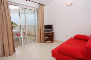 a living room with a red couch and a television at Apartments by the sea Postira, Brac - 705 in Postira