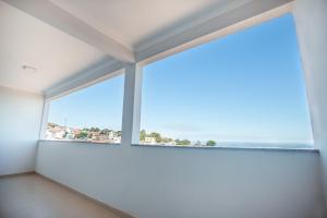 a room with a large window with the ocean in the background at Souza Reis Apart - Unidade 1 in São Thomé das Letras