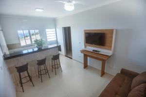 uma sala de estar com televisão e um bar com bancos em Souza Reis Apart - Unidade 1 em São Thomé das Letras
