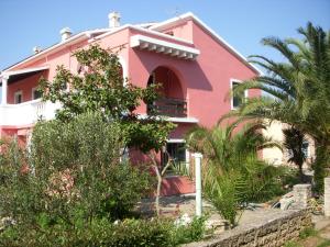 ein rosafarbenes Haus mit Bäumen davor in der Unterkunft Apartments by the sea Susica, Ugljan - 841 in Ugljan