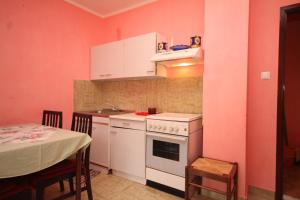 eine Küche mit rosa Wänden, einem Tisch und einem Herd in der Unterkunft Apartments by the sea Susica, Ugljan - 841 in Ugljan