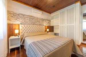 Vila Suzana Parque Hotel في كانيلا: غرفة نوم بسرير وجدار من الطوب