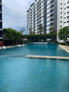 uma grande piscina de água azul em frente aos edifícios em Orak Villa Homestay at Suria Residence em Shah Alam