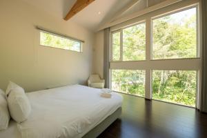a bedroom with a bed and two large windows at Annupuri Onsen Chalet in Niseko