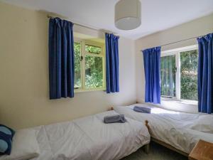 2 camas en una habitación con cortinas azules en Fossil And The Cross Cottage, en Swyre