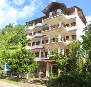 a tall white building with trees in front of it at Ba Be Legend Hotel & Tours in Ba Be18